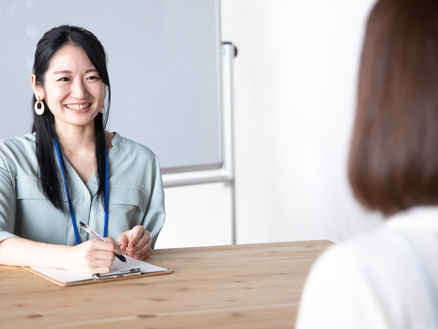 笑顔の女性と、対面でコミュニケーション訓練をしている写真